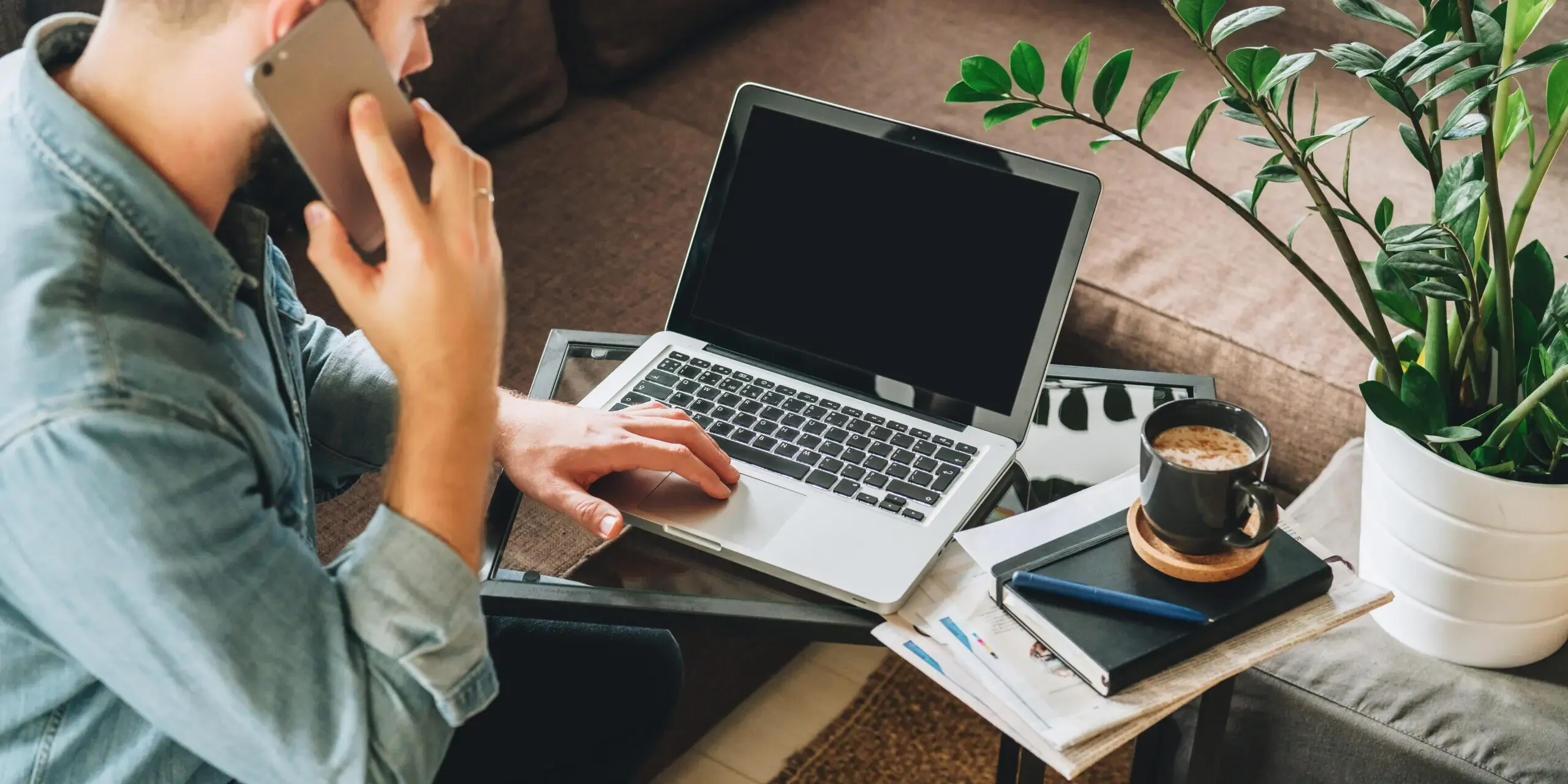 Man working on laptop, talking on phone.